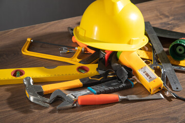 Work tools with helmet on wooden background.