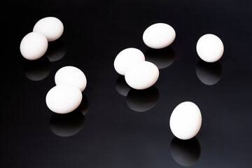 white chicken eggs lie on a black mirror background