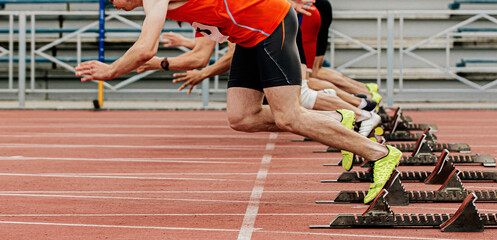 start race male athletes runners running in starting blocks