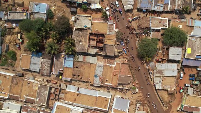 An aerial top view of an Indian village with old buildings and people moving on road