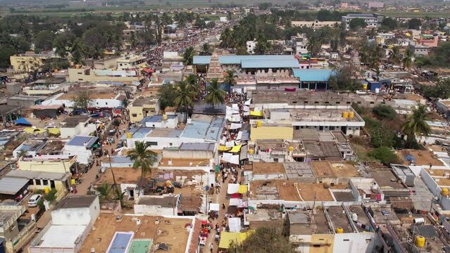 Aerial view of a temple in the middle of a village with a crowd of devotees moving on temple road