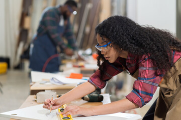 Woman carpenter using precision level making furniture at wood workshop