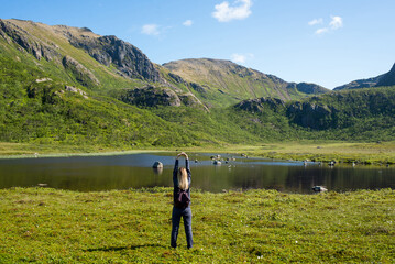 Young woman enjoy the beautiful natural scenery in the north. Lake and mountains. Tourist attraction in Norway. Amazing scenic outdoor view. Travel, adventure, relaxed lifestyle. Lofoten Islands