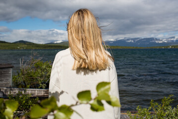 Fototapeta premium Young woman enjoy the beautiful natural scenery in the north. Lake and mountains. Tourist attraction in Norway. Amazing scenic outdoor view. Travel, adventure, relaxed lifestyle. Lofoten Islands