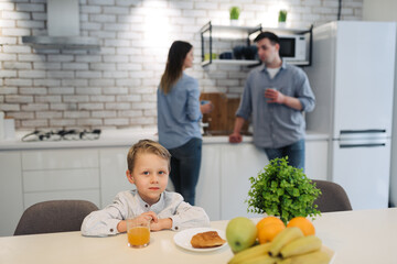 Young couple having coffee together at home in the kitchen while their son have a breakfast