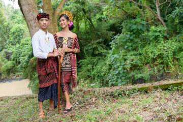 balinese couple walking in tropic forest wearing kebaya or traditional costume