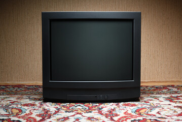 A vintage TV sits on a carpet, an old house design in the style of the 1980s and 1990s.