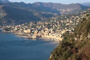 Fototapeta premium Camogli, Italy - January 27, 2023: Beautiful old mediterranean town at the sunrise time with illumination during winter days. People enjoying the evening at the beach with beautiful sunset background