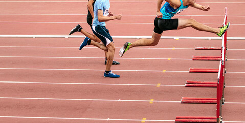 race men athletes run 110 meters hurdles in athletics competition