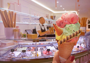 Italian ice - cream cone held in hand on the background of  shop  in Rome , Italy .It is one of the best ice cream place in town popular among tourists - 572728507