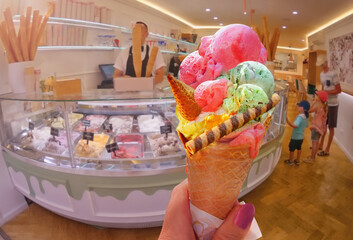 Italian ice - cream cone held in hand on the background of  shop  in Rome , Italy .It is one of the best ice cream place in town popular among tourists