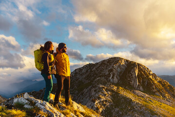 a couple of hikers equipped with mountain equipment, warm clothes and a backpack on top of a...