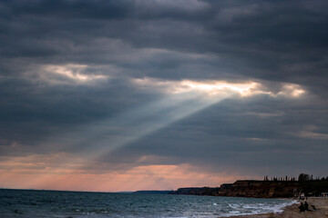The rays of the sun break through the clouds in the sky and fall into the sea	
