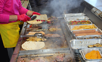 cook in the street food stall preparing a stuffed sandwich with meat and vegetables