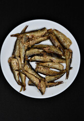 Canned fish on a white plate. Sprats and a fork. Fish in oil. Breakfast of fish.