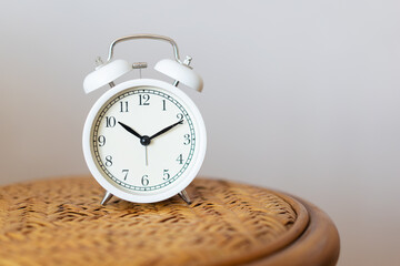White minimalist design alarm clock on rattan chair