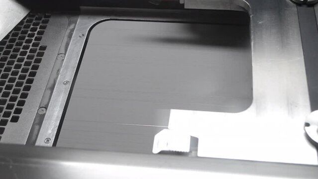 Alignment of metal powder on working surface of 3D printer for metal before starting work. Gray material metal powder for printing objects by 3d printer for metal. Working 3d printer inside.