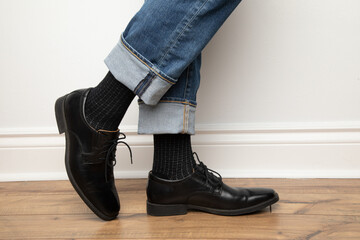 Product photo of men's footwear. This is a close up on a man wearing black leather dress shoes,...