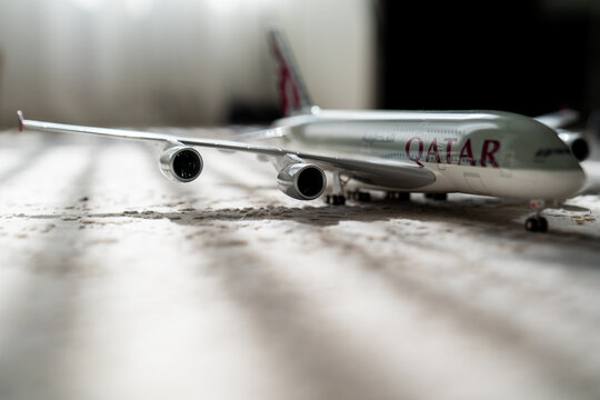 Qatar airways aircraft model. Aviation industry creative effect with sun light beam, airplane aircraft toy on grey background with lines, travelling concept. Trip on passenger get 