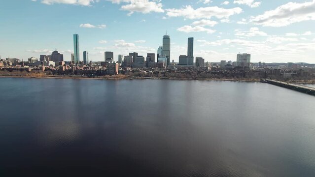 Drone and aerial establishing moving shot towards high-rise skyscrapers, tall apartments, and business developments in downtown Boston, Massachusetts on a sunny, winter day near the Charles River