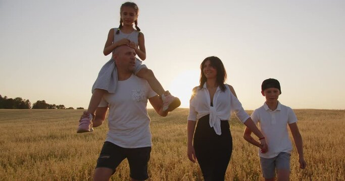 A young happy family with children is walking in the field - Powered by Adobe