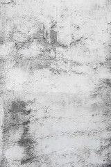 Vertical close-up photo of old plaster on a white wall, which has fallen off in places due to time and weather conditions