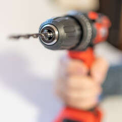 Men's hand holding an electric drill with batteries without cables on a white background.