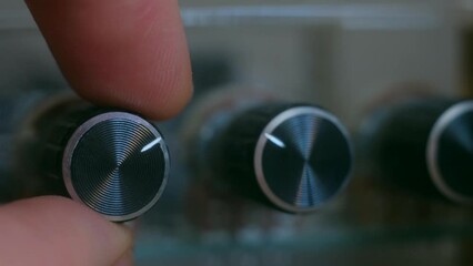 close-up - finger of person controls the volume balance of the amplifier, turns adjustment audio frequency. slowmotion