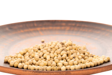 Fragrant vegetable coriander seeds in a clay plate, macro, isolated on white background.