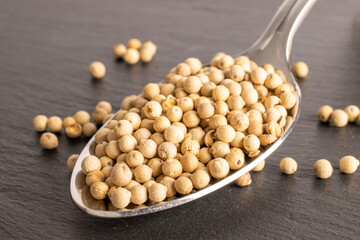 Fragrant vegetable coriander seeds in a metal spoon on a slate stone, macro.