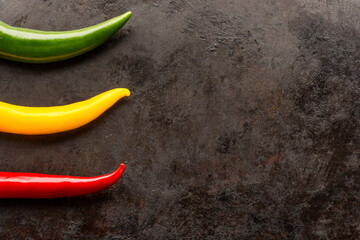 red yellow and green chili peppers on rusty metal table