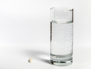 A glass of water and a capsule pill or medicine drug on white background.