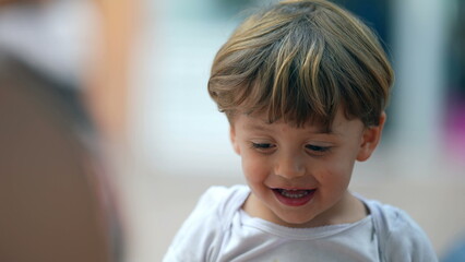 One little baby boy happy expression closeup face. Authentic real life toddler child laugh and smile outdoors. 2 year old kid