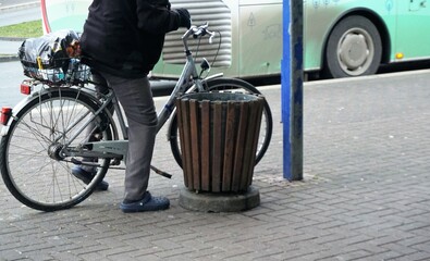 Alter Mann mit grauer Hose und schwarzem Pullover auf silbernem Fahrrad nach Flaschenleergut...