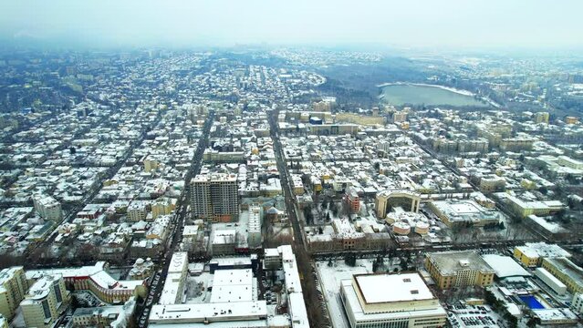 Aerial drone view of Chisinau in winter, Moldova. View of the city with multiple buildings and roads covered with snow, Valea Morilor park with lake and bare trees