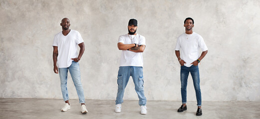 Collage of three different men full body against textured gray wall, dressed in jeans and white...