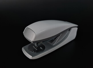 Gray stapler isolated on black background. Stationery