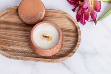 Interior candle in plaster candlestick and tulip on marble background. Candle on wooden tray. Top view