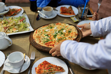 pizza on a wooden board is served in a street cafe