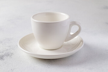 White empty cup for coffee on a plate isolated on the table