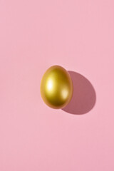 Fototapeta na wymiar Easter template with golden egg. Egg painted gold on pink background. Easter concept with copy space for text. Flat lay style minimalistic design.