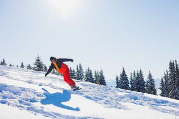 A snowboarder walks down a snowy slope in winter on the snow. Snowboarding, winter freeride