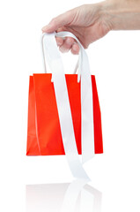 Red shopping bag with ribbons in hand isolated on white background