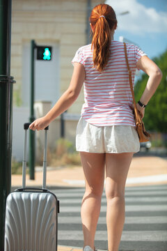 beautiful woman with suitcases crossing the street