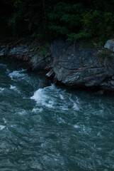 Mountain river with clear water near rock in Alps