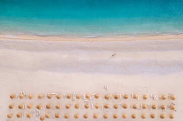 Sun umbrellas rows and sunbeds Myrtos Beach unique turquoise water seashore with a bright white pebbles often proclaimed as one of best beaches in Greece. Kefalonia island aerial background photo.