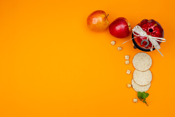 Ripe apples, matzah, pomegranate, nuts and mint leaves on orange background