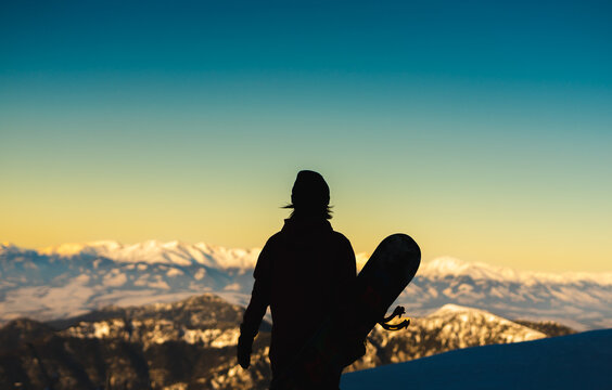 silhouette of a woman  with snowboard on mountain's top. 
