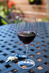 Glass of red wine and car keys outdoors on patio table.
