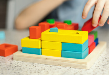 Close-up of children's hands playing with an educational multi-colored puzzle toy made of...